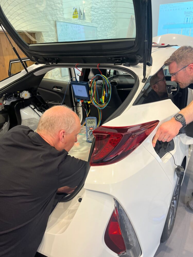 2 learners conducting tests on the AC charging circuit of a Toyota PHEV Prius.