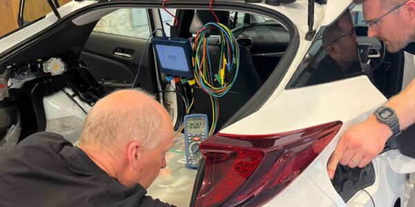 2 learners conducting tests on the AC charging circuit of a Toyota PHEV Prius.